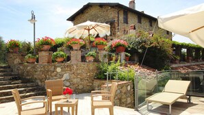 Un bâtiment en pierre doté d’un balcon, de meubles en osier et de plantes en pot.