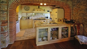 Une cuisine rustique avec une arche en briques, des armoires en bois et une table à manger agrémentée de verres.