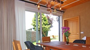 A dining area with a wooden table, chairs, and a vase of flowers. - Ferienwohnung Strandanker in Monkebude (Monkebude)