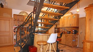 A kitchen with wooden cabinets, a wooden staircase, and a red chair. - Ferienwohnung Strandanker in Monkebude (Monkebude)