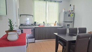 A compact kitchen with a dining area, a refrigerator, and a small table with chairs.