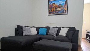 A sectional sofa with a matching ottoman in a living room with wooden flooring.
