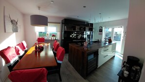 Una cocina moderna con comedor, que presenta una mesa de madera, sillas rojas y un amplio ventanal con vistas.