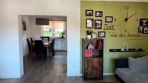 Una sala de estar moderna con una pared de acento verde, un comedor con vistas y una estantería.