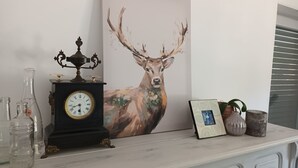 Una repisa con un reloj, un cuadro enmarcado de un ciervo y adornos decorativos.