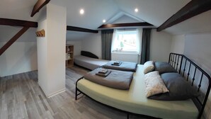 Un dormitorio pequeño con cama, mesita de noche, ventana con cortinas y estante empotrado.