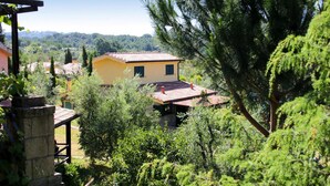 Un bâtiment jaune avec un toit rouge, entouré d’une végétation luxuriante et d’arbres.