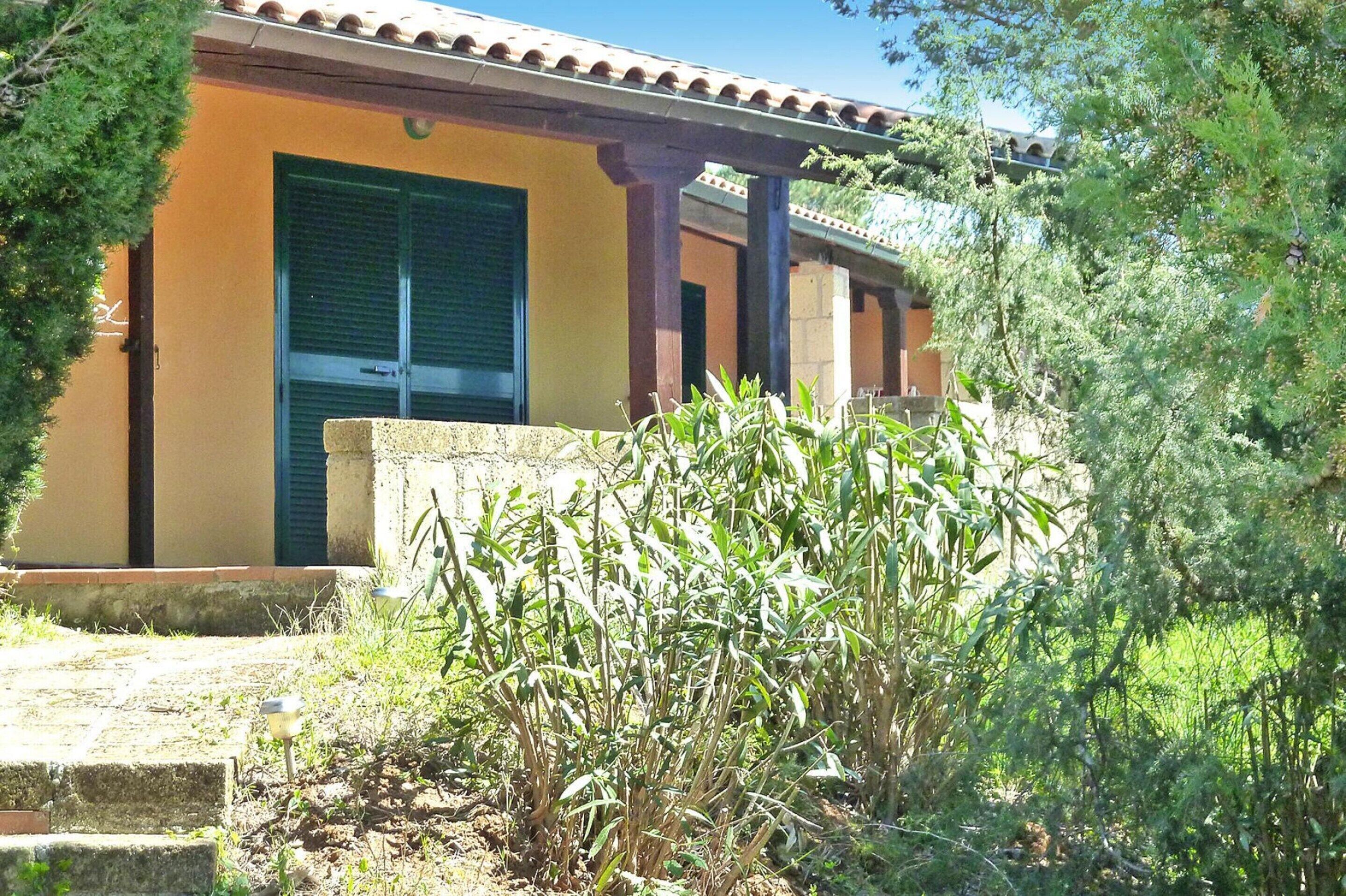 A building with a yellow facade, green shutters, and a tiled roof.