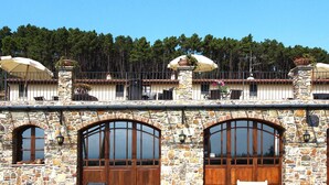 A stone building with arched windows and balconies with umbrellas. - Estate in Monte Serra With Pool & Olive Trees (Buti)
