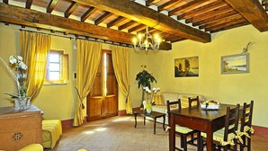 A dining area with a wooden table and chairs, a sofa, and a chandelier. - Estate in Monte Serra With Pool & Olive Trees (Buti)
