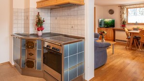 Una cucina compatta con forno a incasso e un piccolo angolo ristoro con televisione.