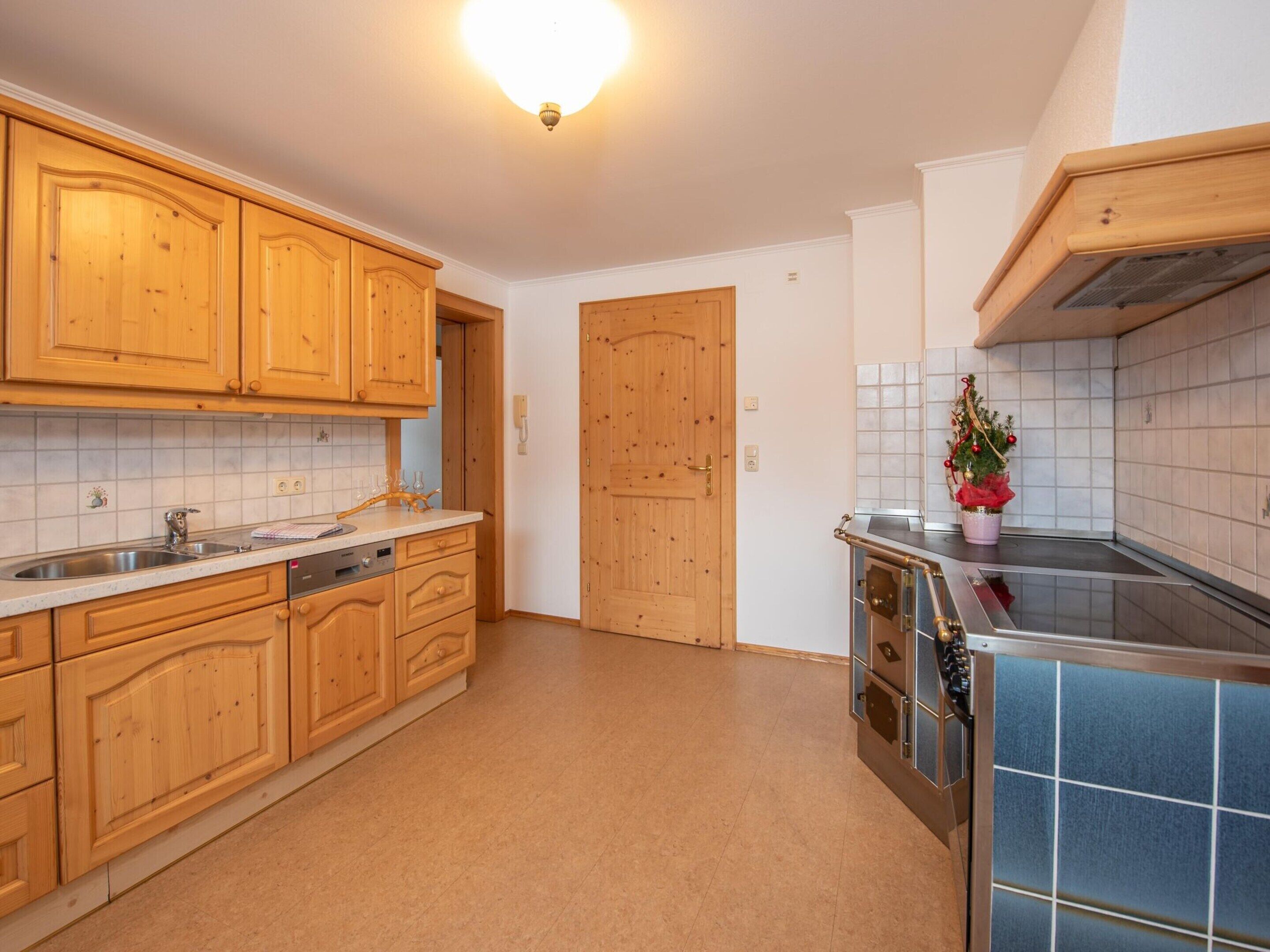 Een keuken met houten kastjes, een roestvrijstalen spoelbak en een betegelde achterwand.