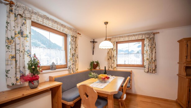 A dining area with a wooden table, benches, and a chandelier. - Apartment in Wald Near Krimml Waterfalls (Wald im Pinzgau)