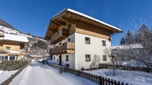 Un edificio a due piani con un balcone in legno e un tetto coperto di neve.
