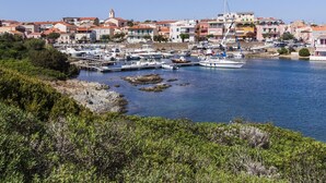 A coastal town with a marina, boats, and buildings with red roofs. - Residence Capo Falcone, Stintino (Stintino)