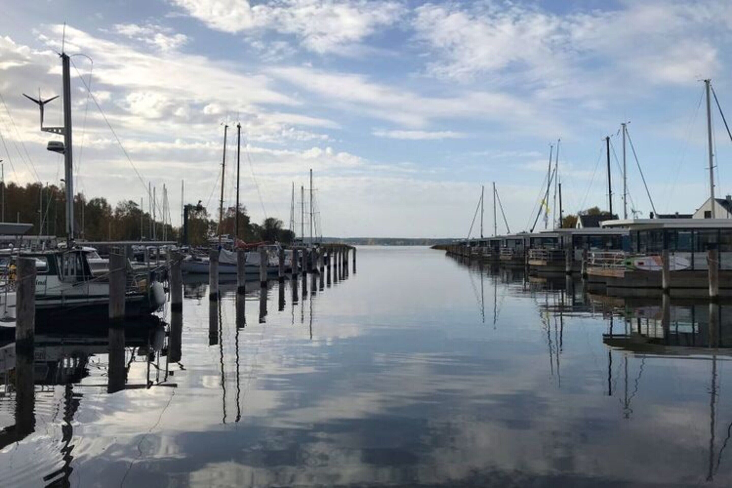Una marina con barcos amarrados a muelles de madera, agua tranquila y cielo despejado.