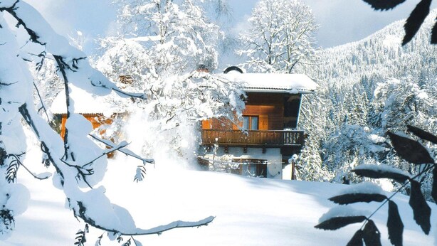 A wooden cabin with a balcony, surrounded by snow-covered trees and a mountainous backdrop. - Apartment in Huttau Near Ski Amade Slopes (Huettau)