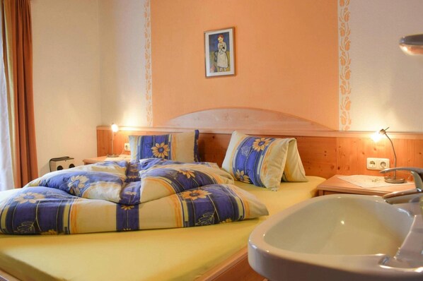 A hotel room with a bed, a bedside table, a lamp, a picture on the wall, and a sink. - Apartment in Huttau Near Ski Amade Slopes (Huettau)