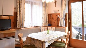 A cozy room with a dining table, chairs, a television, and a window with curtains. - Apartment in Huttau Near Ski Amade Slopes (Huettau)