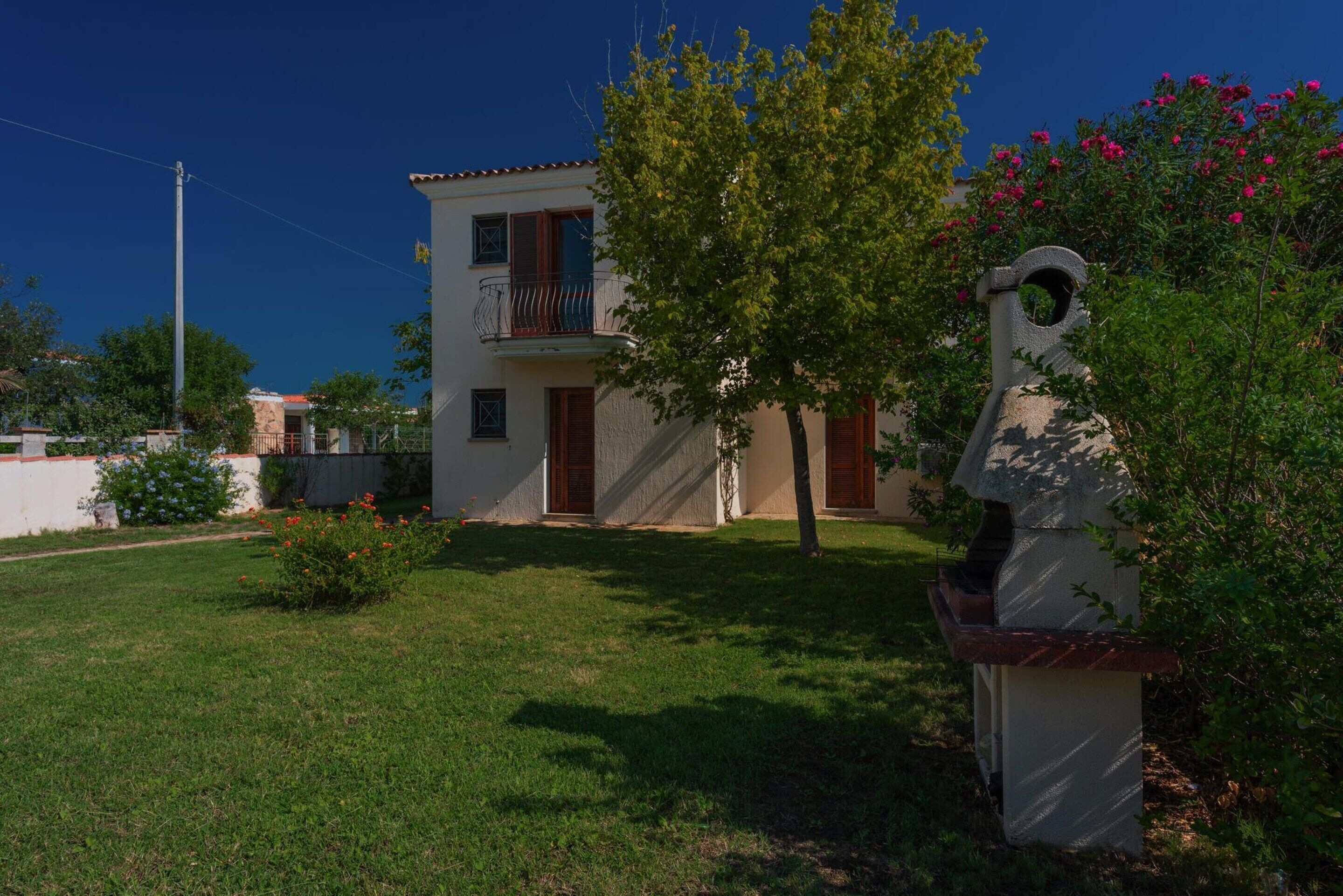 A two-story building with a balcony, a well-maintained lawn, and a stone sculpture.