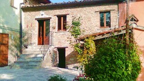 Un bâtiment en pierre avec une porte en bois, une petite fenêtre et un escalier menant à un porche.