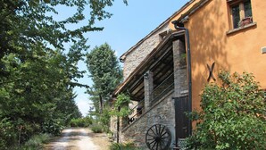 Un bâtiment rustique avec une façade en pierre, une porte en bois et une grande roue visible de l’extérieur.