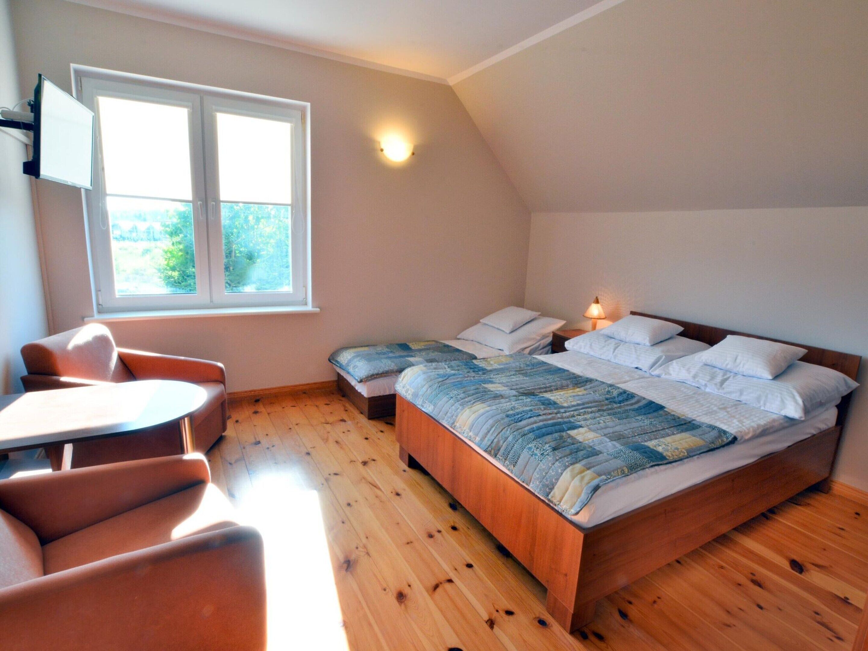 Une chambre à coucher avec un lit, deux tables de chevet, une chaise et une fenêtre.