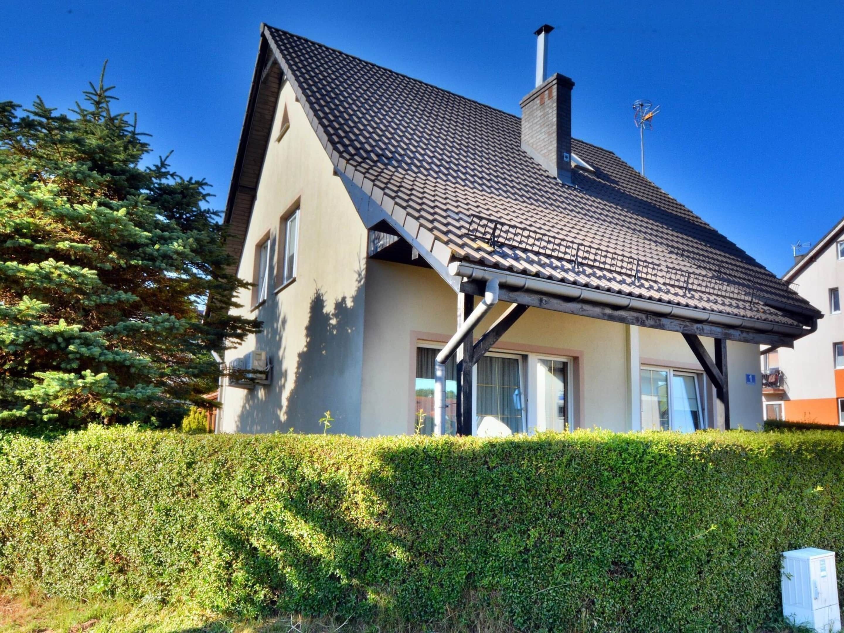A two-story house with a tiled roof, a chimney, and a small porch.