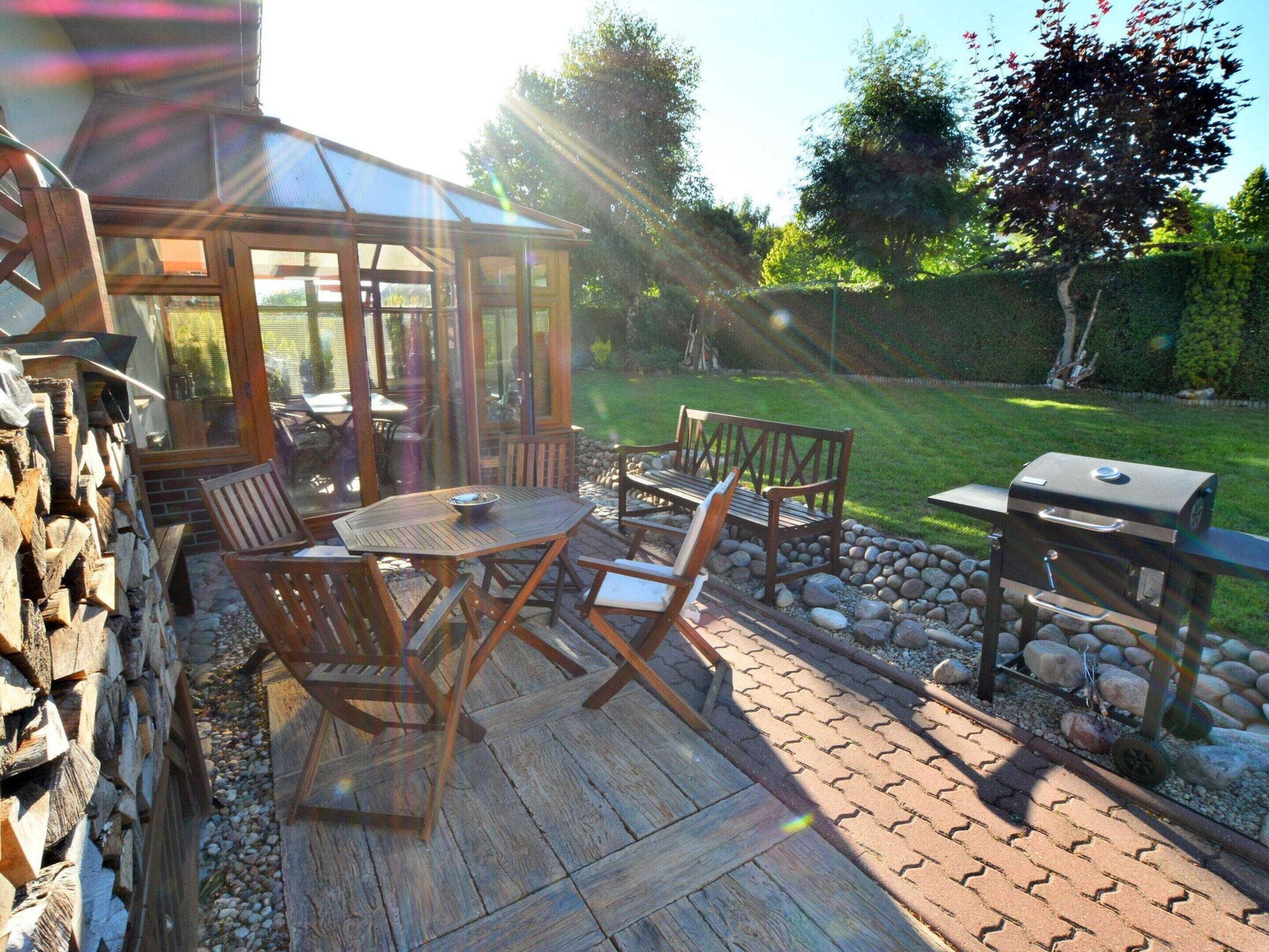 A patio with wooden furniture, a grill, and a stone wall.