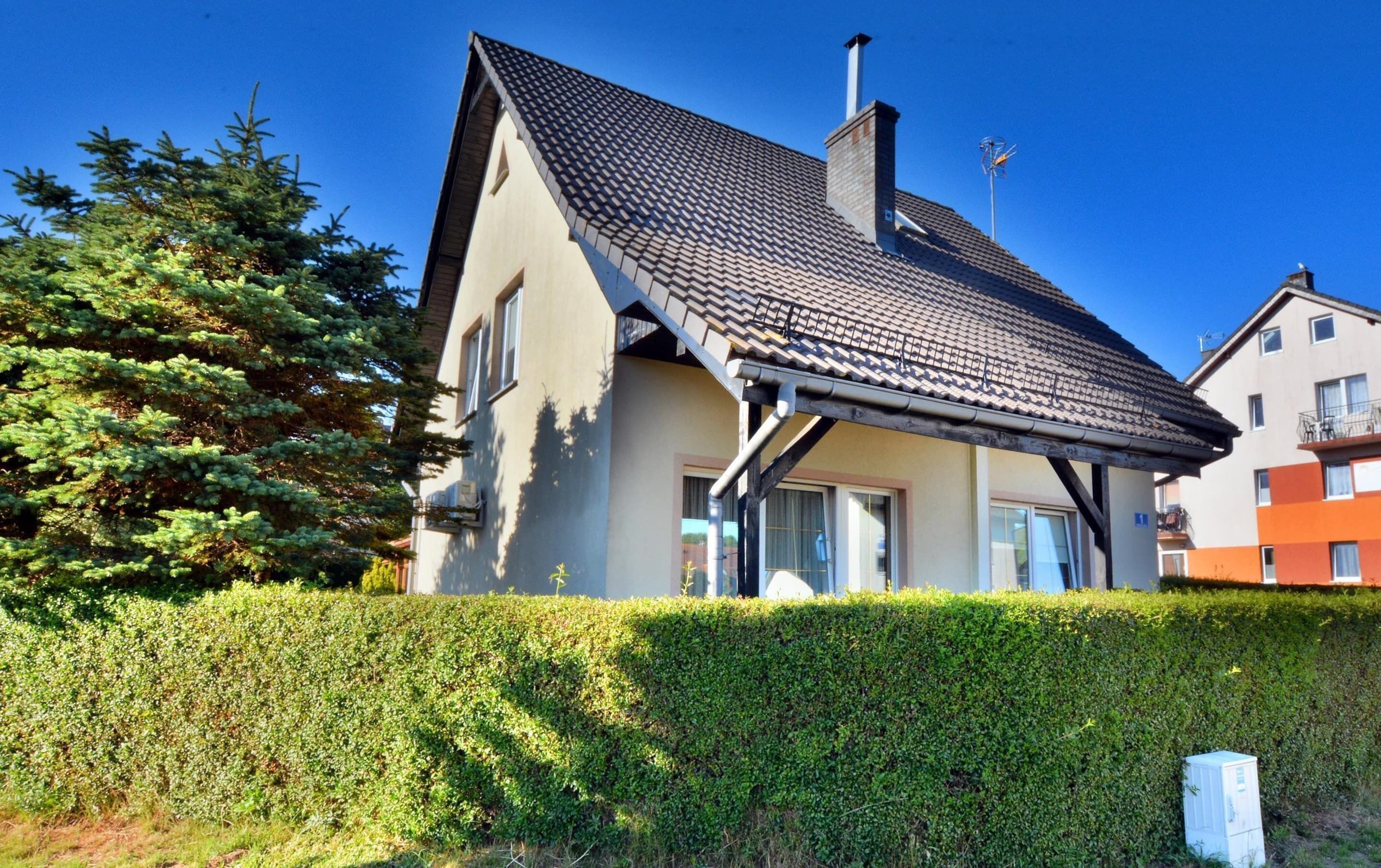A two-story house with a sloped roof, a chimney, and a small balcony.