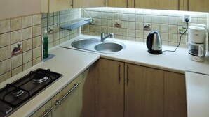 Une cuisine équipée d’une cuisinière à gaz, d’un évier, d’une bouilloire et d’une machine à café.