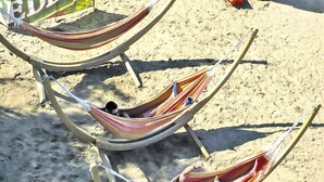 Trois hamacs sur une plage de sable.