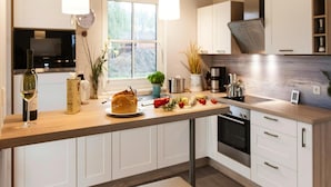 A modern kitchen with white cabinets, a wooden countertop, and pendant lighting. - Komfortables Ferienhaus mit Sauna in Fuhlendorf (Fuhlendorf)