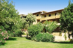 A multi-story building with balconies, surrounded by lush greenery and a well-maintained lawn. - Apartment in Porto Rotondo Near Sandy Beach (Olbia)
