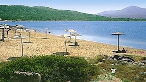 Ein Strand mit Sonnenschirmen und einem Berg im Hintergrund.