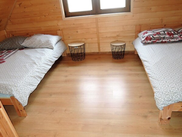 A cozy cabin with two wooden beds, each with patterned bedding, and a small round table between them. - Family Resort in Niechorze Near Lighthouse (Rewal)