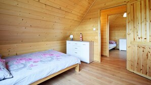 A cozy wooden room with a bed, a dresser, and a small desk. - Family Resort in Niechorze Near Lighthouse (Rewal)