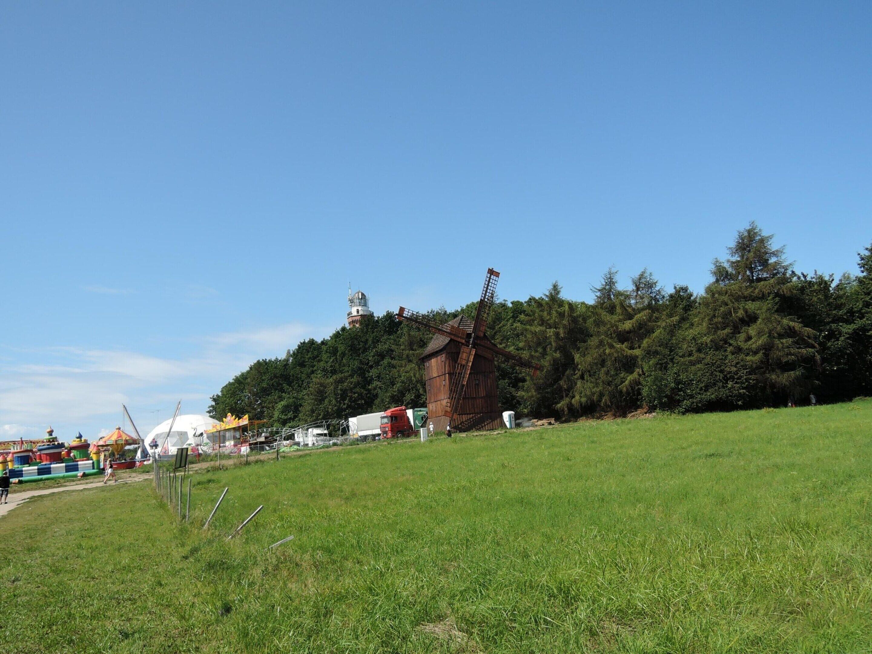 A windmill on a hill with a clear sky.
