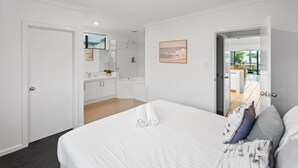 A bedroom with a bed, a bathroom with a shower, and a view of the outside.