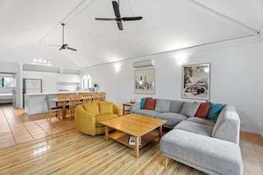 A spacious living area with a sofa, coffee table, and dining set.