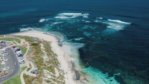 An aerial view of a coastal area with a parking lot, beach, and ocean.