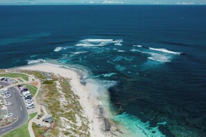 Vue aérienne d’une zone côtière comprenant un parking, une plage et l’océan.