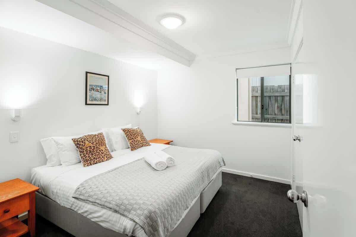 Ein Hotelzimmer mit Bett, Nachttisch, einem gerahmten Bild an der Wand und einem Fenster mit Blick.