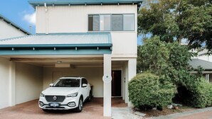A two-story building with a covered driveway and a parked car.