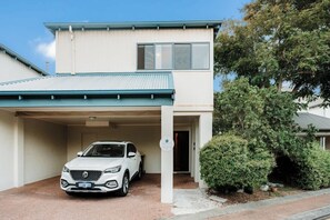 A two-story building with a covered driveway and a parked car.