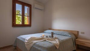 Ein Schlafzimmer mit Bett, Nachttisch, Fenster und Klimaanlage.
