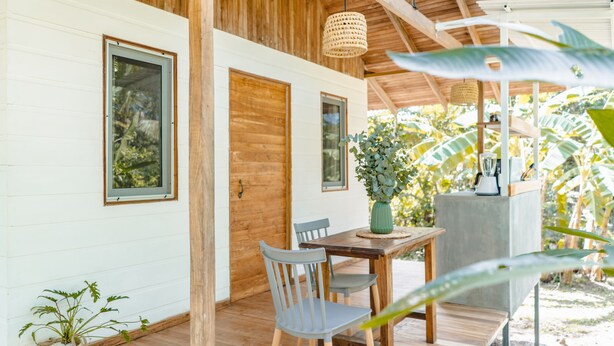 Una terraza de madera con una mesa, sillas, una lámpara colgante y una planta en maceta.