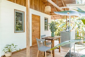 A wooden deck with a table and chairs, a hanging light fixture, and a potted plant. - Cuatro Vientos Costa Rica (Cóbano)