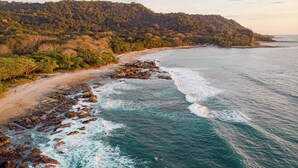 Un paisaje costero con una playa, costa rocosa y colinas boscosas.
