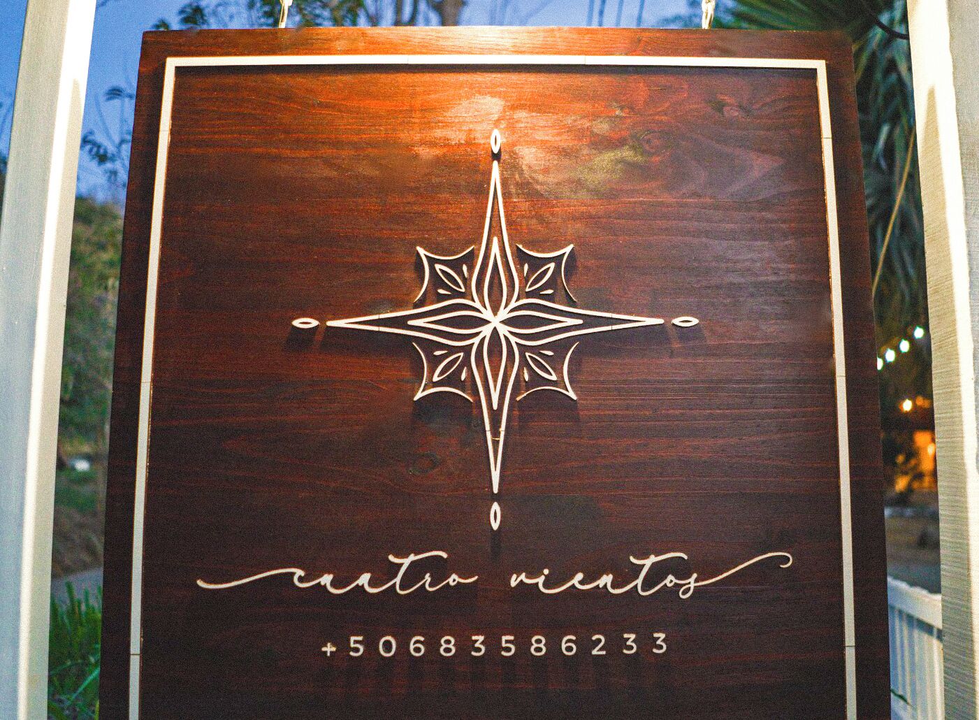 A wooden plaque with a compass design and the text "ciento minutos" and a phone number.